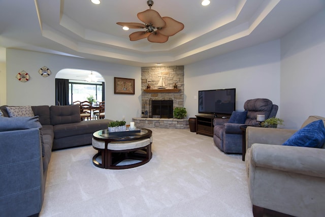 living room featuring arched walkways, ceiling fan, and a raised ceiling