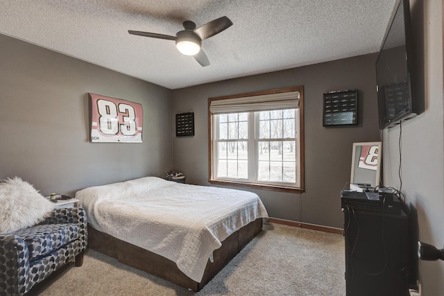 carpeted bedroom featuring ceiling fan, a textured ceiling, and baseboards