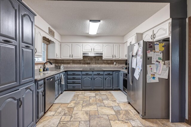 kitchen featuring backsplash, appliances with stainless steel finishes, stone finish floor, white cabinetry, and under cabinet range hood