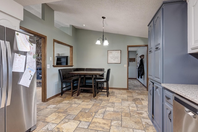 kitchen with a notable chandelier, stone tile flooring, light countertops, appliances with stainless steel finishes, and vaulted ceiling