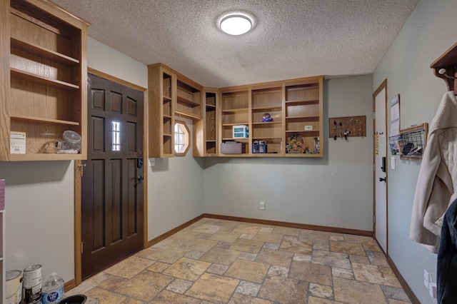 entrance foyer featuring baseboards, a textured ceiling, and stone tile floors