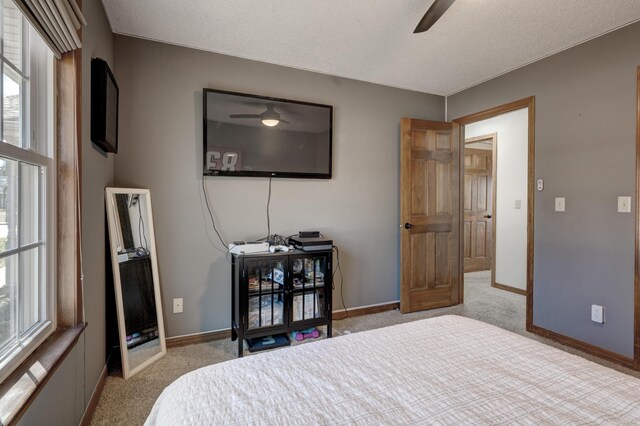 carpeted bedroom with a textured ceiling, a ceiling fan, and baseboards