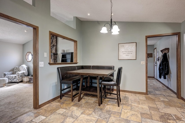 dining area featuring stone tile floors, baseboards, a chandelier, and a textured ceiling