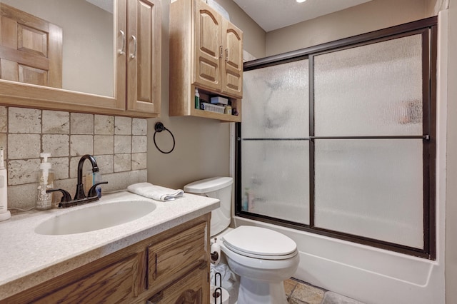 bathroom featuring tasteful backsplash, combined bath / shower with glass door, vanity, and toilet