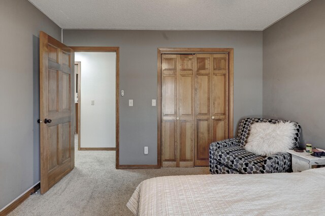 carpeted bedroom featuring a textured ceiling, baseboards, and a closet