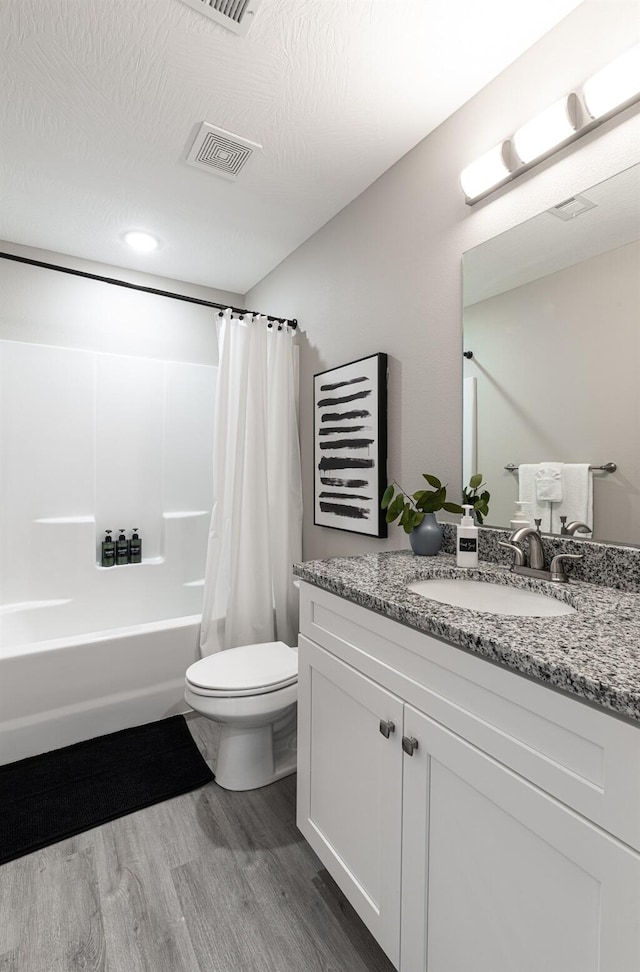 full bath featuring visible vents, toilet, wood finished floors, shower / bath combination with curtain, and vanity