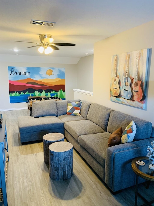 living area with vaulted ceiling, wood finished floors, visible vents, and a ceiling fan