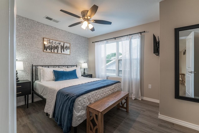 bedroom with baseboards, an accent wall, visible vents, and wood finished floors