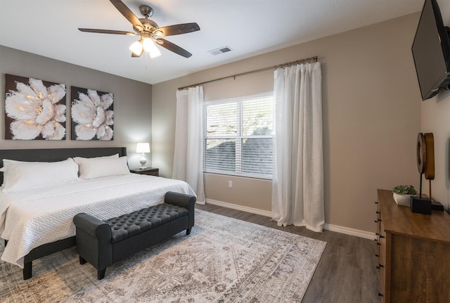 bedroom featuring a ceiling fan, visible vents, baseboards, and wood finished floors