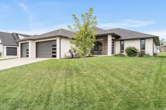 prairie-style house with brick siding, a shingled roof, a garage, driveway, and a front lawn