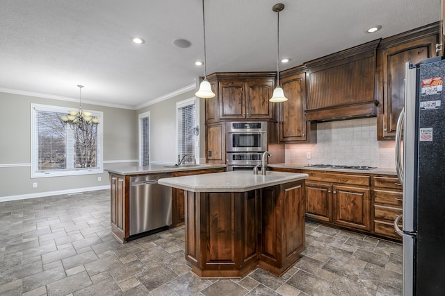 kitchen with light countertops, appliances with stainless steel finishes, stone finish floor, a kitchen island with sink, and a sink