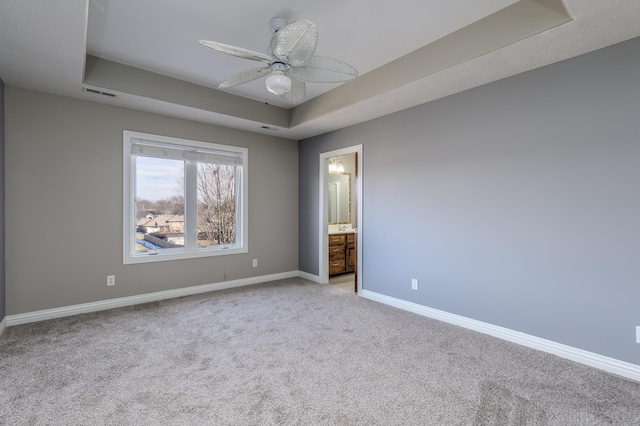 unfurnished bedroom featuring light carpet, baseboards, visible vents, and a tray ceiling