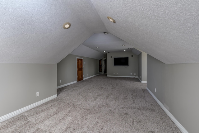 bonus room featuring vaulted ceiling, a textured ceiling, carpet flooring, and baseboards