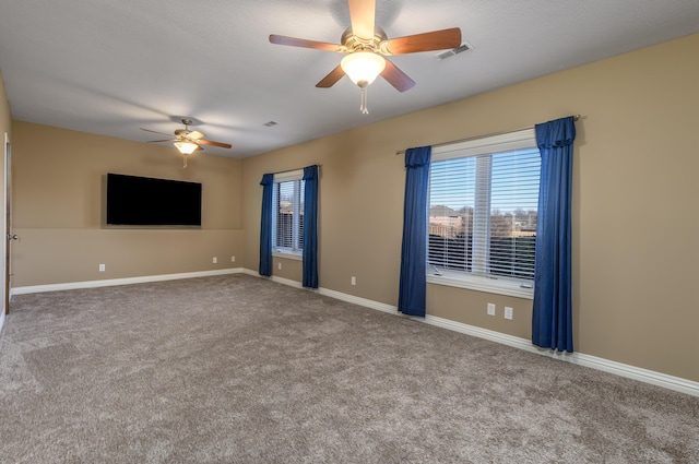 carpeted empty room featuring a ceiling fan, visible vents, and baseboards