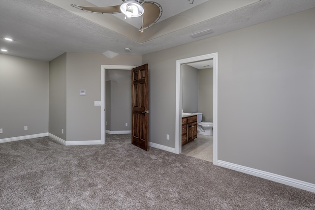 unfurnished bedroom with visible vents, baseboards, light colored carpet, ensuite bathroom, and a textured ceiling