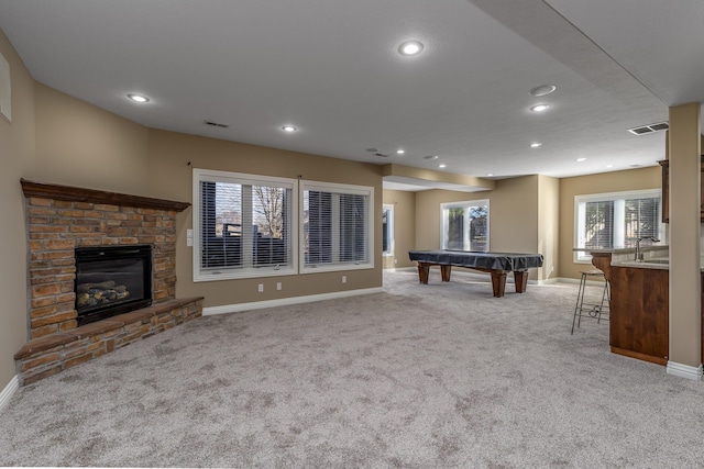 recreation room featuring a stone fireplace, recessed lighting, light carpet, visible vents, and baseboards