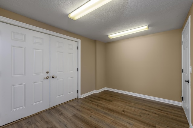 spare room featuring dark wood-style flooring, a textured ceiling, and baseboards