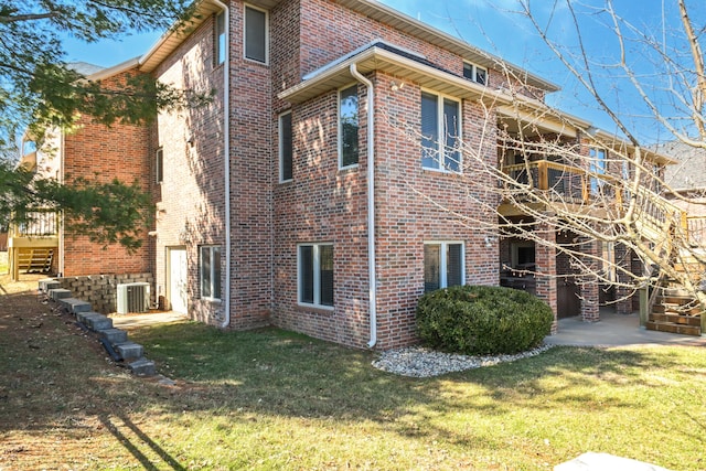 view of home's exterior with brick siding, a yard, and central AC unit