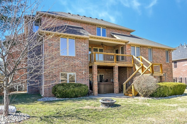 rear view of house with a fire pit, roof with shingles, stairs, a yard, and brick siding