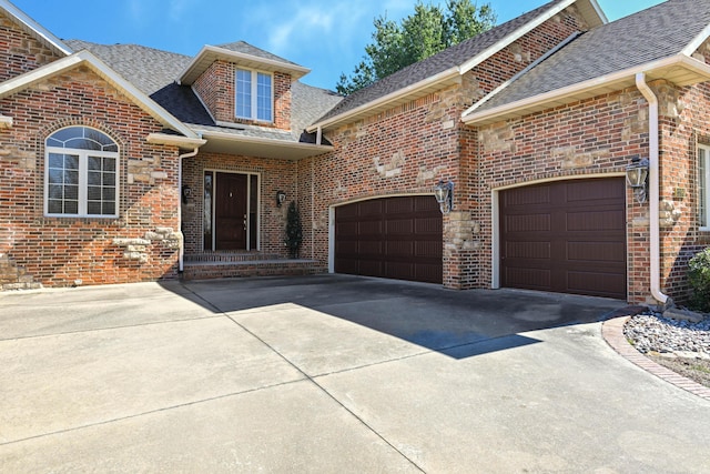 traditional-style home featuring a garage, brick siding, driveway, and roof with shingles