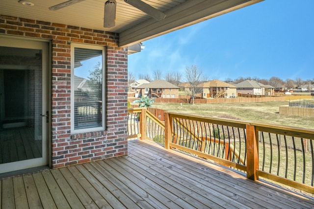 wooden terrace with ceiling fan, fence, and a residential view