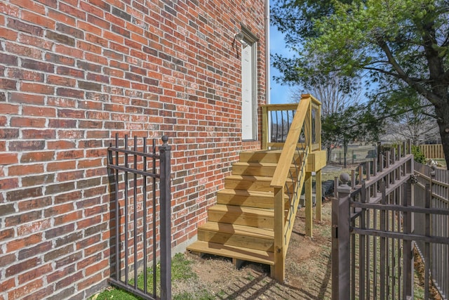 doorway to property featuring brick siding and fence