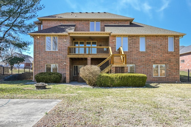 back of property featuring brick siding, a lawn, stairway, fence, and a fire pit