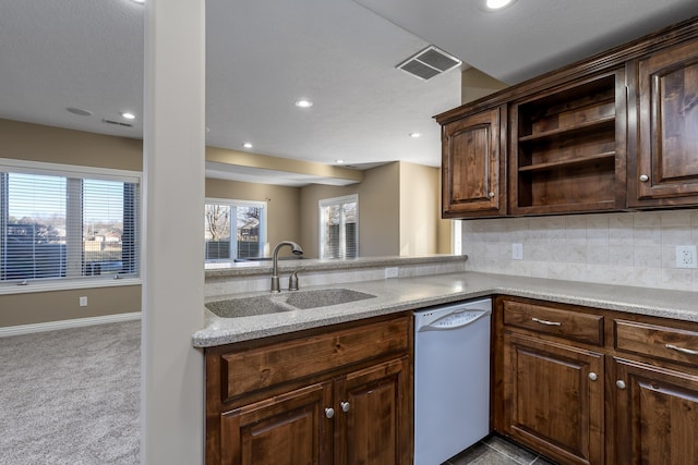 kitchen with carpet, visible vents, backsplash, white dishwasher, and a sink