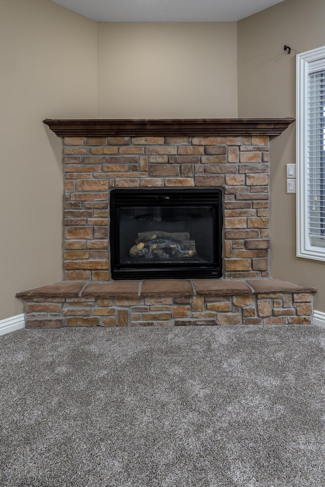 interior details featuring carpet floors, a stone fireplace, and baseboards