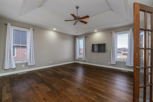 unfurnished room with dark wood-style floors, plenty of natural light, a raised ceiling, and baseboards