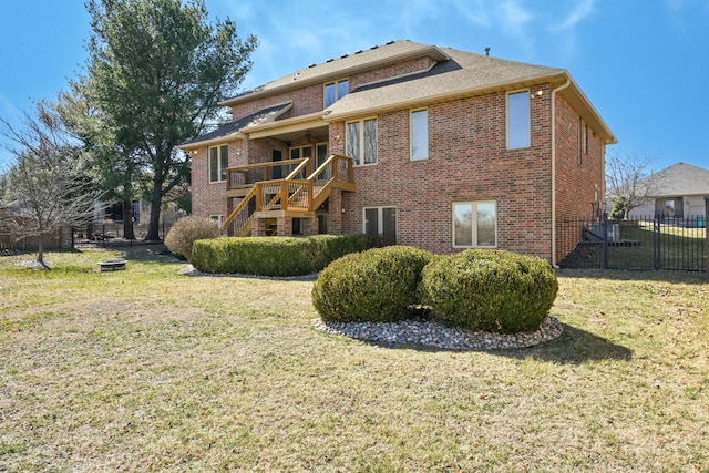 rear view of property featuring brick siding, a yard, and fence