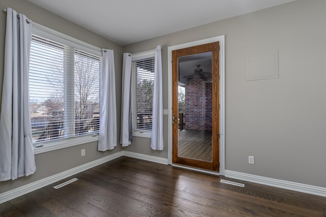 unfurnished room featuring dark wood-style floors, visible vents, and baseboards