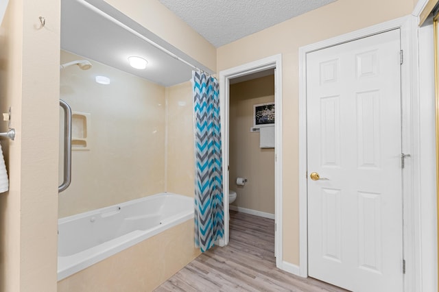 bathroom featuring a textured ceiling, toilet, wood finished floors, baseboards, and shower / bath combo with shower curtain