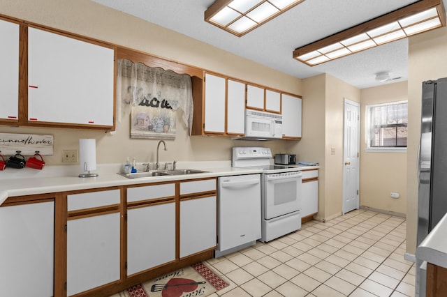 kitchen with light countertops, white appliances, a sink, and white cabinetry