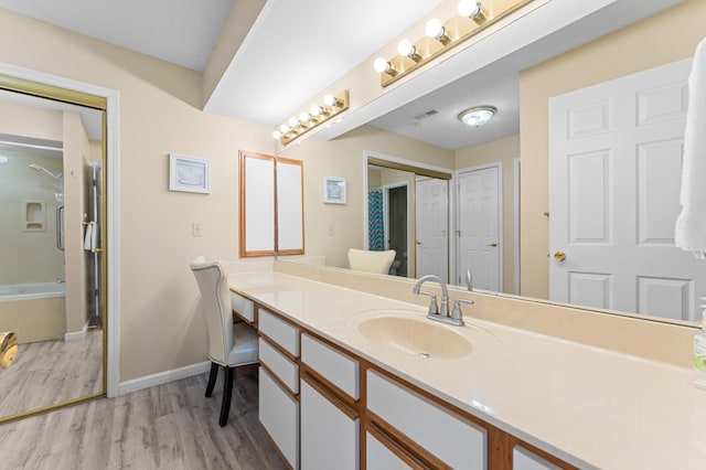 bathroom with bathtub / shower combination, wood finished floors, visible vents, vanity, and baseboards