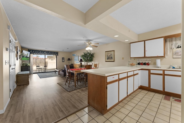 kitchen with open floor plan, light countertops, a peninsula, and white cabinetry