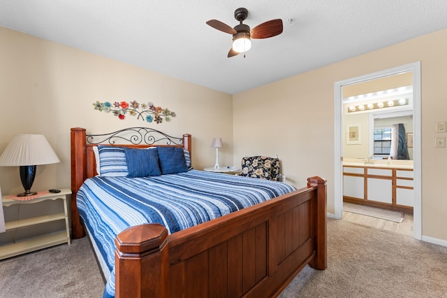 carpeted bedroom featuring baseboards, a ceiling fan, ensuite bathroom, a textured ceiling, and a sink