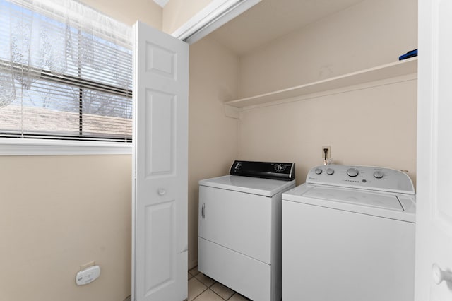 clothes washing area featuring light tile patterned floors, laundry area, and washer and clothes dryer