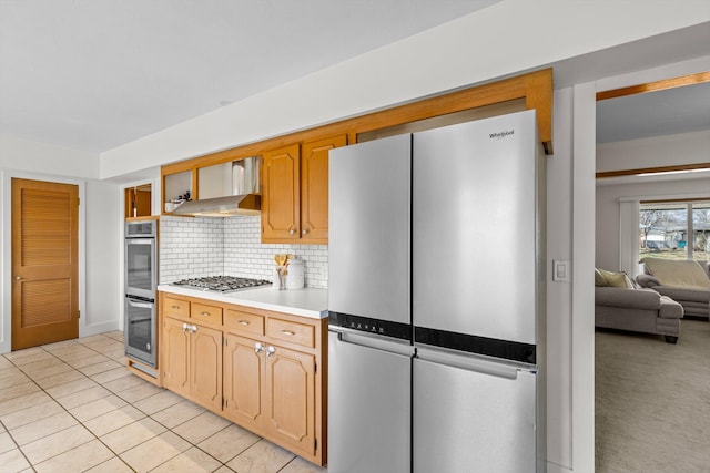 kitchen featuring light tile patterned floors, stainless steel appliances, light countertops, backsplash, and ventilation hood