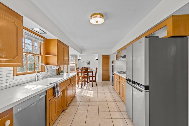 kitchen with light tile patterned flooring, a sink, exhaust hood, light countertops, and appliances with stainless steel finishes