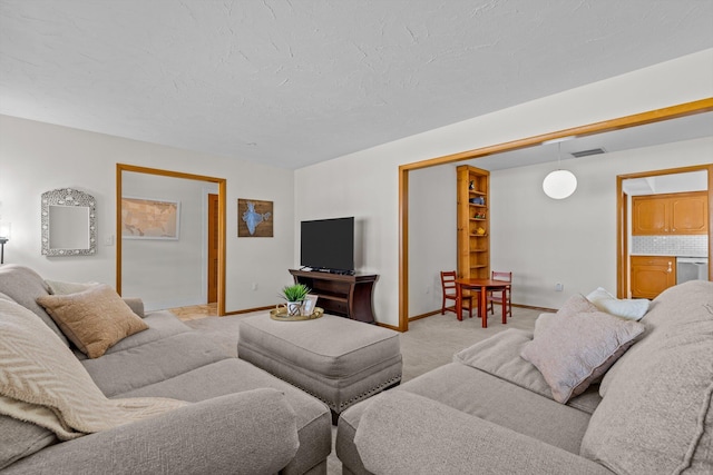 living room with baseboards, visible vents, a textured ceiling, and light colored carpet