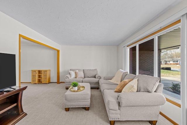 carpeted living room with a textured ceiling and baseboards