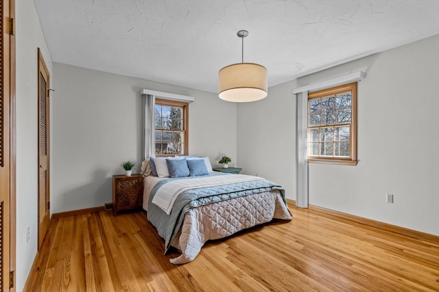 bedroom with baseboards, a textured ceiling, and light wood finished floors