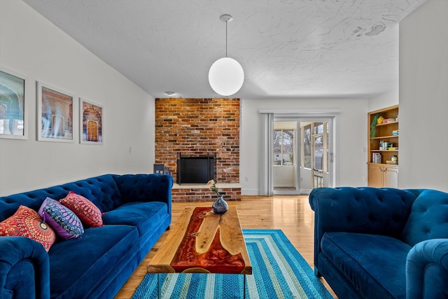 living room featuring built in features, a fireplace, a textured ceiling, and wood finished floors