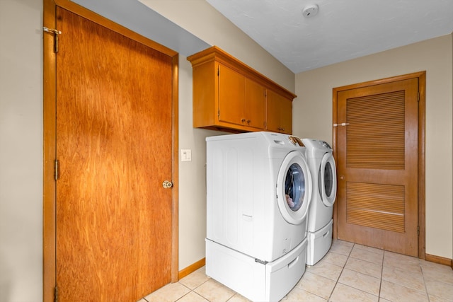 washroom with light tile patterned floors, washing machine and dryer, cabinet space, and baseboards