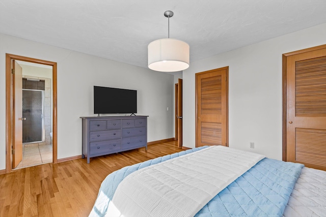 bedroom featuring light wood-type flooring, baseboards, and two closets