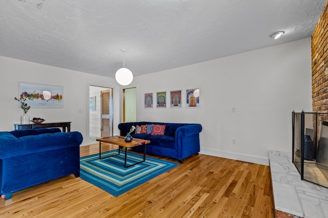 living room with light wood-type flooring, baseboards, and a textured ceiling