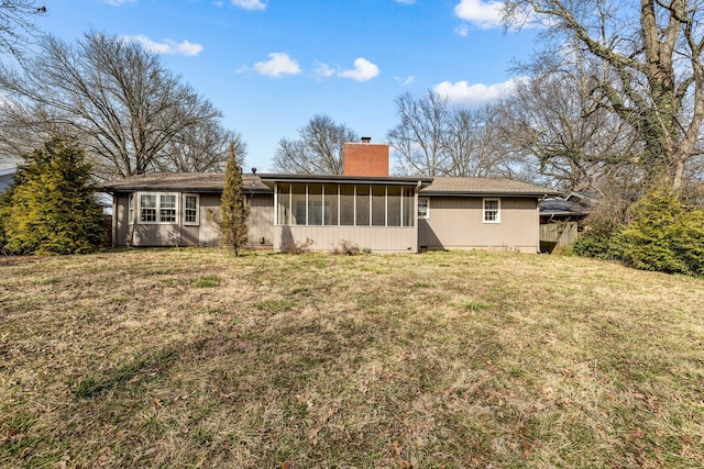 back of house featuring a sunroom, a chimney, and a yard