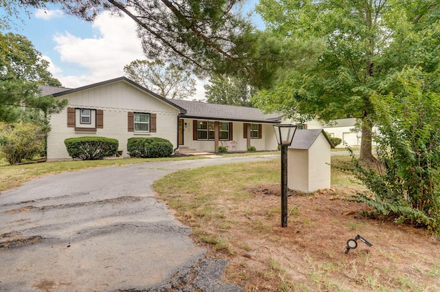 ranch-style home with driveway, an outbuilding, and brick siding