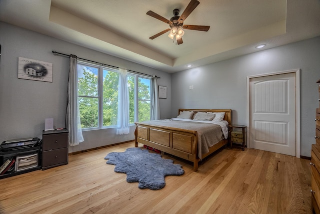 bedroom with recessed lighting, a raised ceiling, a ceiling fan, light wood-type flooring, and baseboards